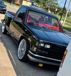 a black truck parked on the side of a road next to a white van and another car