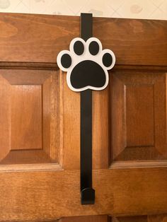 a black and white paw print on a wooden door with a metal hook in front of it