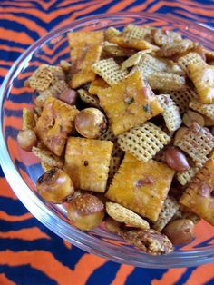 a glass bowl filled with cheetos and nuts on top of a zebra print table cloth