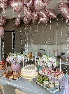 a table topped with lots of desserts and balloons hanging from the ceiling above it