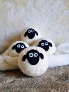 three black and white sheep slippers sitting on top of a stone floor next to a wall