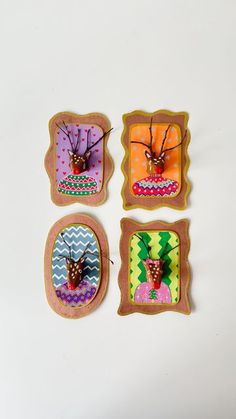 four cookies decorated with different designs and shapes on white surface, including one in the shape of a bug