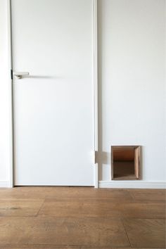 an empty room with a white door and a brown litter box in the corner on the floor