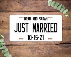 a license plate with the words just married on it next to some green plants and leaves