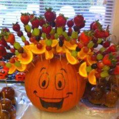 a pumpkin decorated with fruit and flowers in the shape of a face