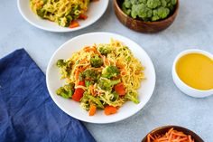 three plates of food with broccoli, carrots and noodles next to dipping sauce