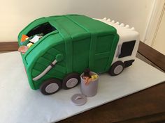 a cake made to look like a green garbage truck with trash cans on the side