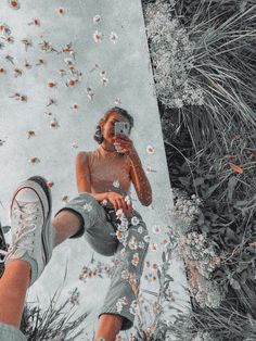 a man taking a selfie with his cell phone in front of flowers and grass