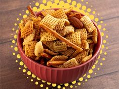 a red bowl filled with cheetos and nuts on top of a wooden table