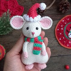 a hand holding a small crocheted mouse with a christmas hat on it's head