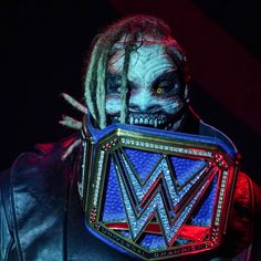 a man with dreadlocks on his face and wearing a wrestling belt in front of him