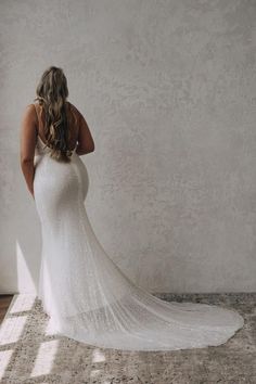 a woman in a white wedding dress is looking down at the floor and back of her gown