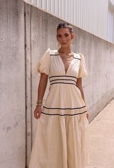 a woman standing next to a wall wearing a dress