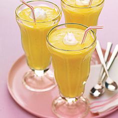 three glasses filled with orange juice on top of a pink plate