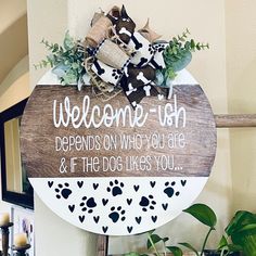 a welcome sign hanging from the side of a wall next to a potted plant