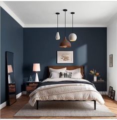 a bed room with a neatly made bed and two lamps hanging from the ceiling above it