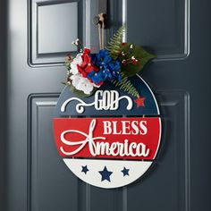 a patriotic door hanger with the words god, bless america and flowers on it