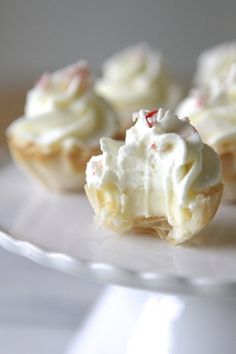 small cupcakes with white frosting and candy canes on a glass plate