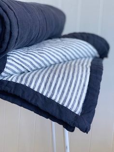 a black and white striped pillow sitting on top of a metal stand next to a wall