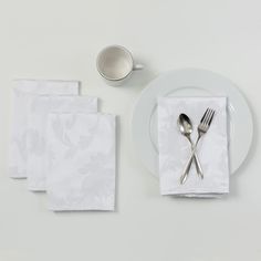 a white plate topped with silverware next to napkins