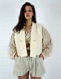 Made in France.Product Description- Short sleeveless jacket,- Beige cotton canvas,- Unstructured glue,- Fully lined, The MUSKEG Jacket is a variation of the DOLMA coat that you love. Designed in beige cotton canvas, the MUSKEG jacket retains the pure, graphic lines of the Louise Marcaud brand while offering the possibility of layering. Over a shirt, sweater or coat. The idea is to play with the codes of layering. Its short cut, and its light material, are ideal for creating sophisticated and rel Beige Cotton Vest Outerwear, Beige Cotton Vest For Winter, Beige Cotton Vest, Chic Cotton Vest For Winter, Fitted Cotton Vest Outerwear, Chic Beige Vest For Fall, Chic Neutral Cotton Outerwear, Fitted Beige Cotton Outerwear, Chic Sleeveless Cotton Outerwear