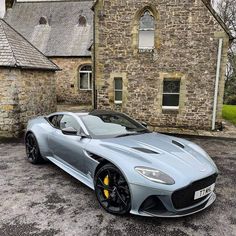 a grey sports car parked in front of a stone building