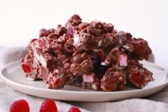 a white plate topped with pieces of chocolate and cherries next to red candies