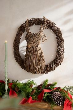 a christmas mantle with pine cones and greenery on it, including a candle holder