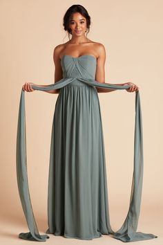 a woman in a strapless dress is holding on to her long, flowing shawl