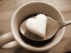 a heart - shaped sugar on a spoon in a cup