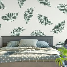 a bed sitting under a green palm leaf wall decal next to a night stand