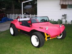 a pink dune buggy parked in front of a white house