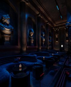 a dimly lit room with blue couches and sculptures on the walls, along with candles