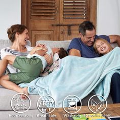 a family laying on a couch under a blanket