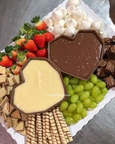 a platter filled with cheese, crackers, strawberries, and chocolate dip