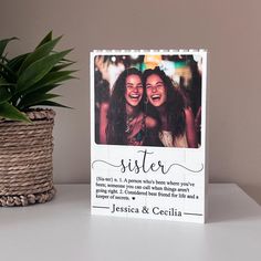 a photo frame with the words sister on it next to a potted plant