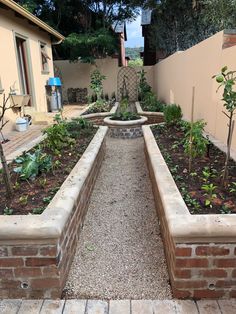 an outdoor garden area with brick walls and plants in the center, surrounded by trees