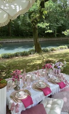 a table set up for a formal dinner in the garden with pink napkins and place settings