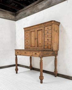 an old wooden desk with drawers on it in a room that has white walls and flooring