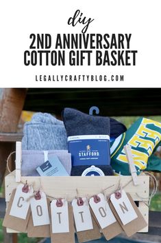 a wooden crate filled with clothes and other items that are on display in front of the words, 2nd anniversary cotton gift basket