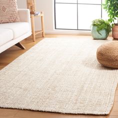 a living room area with a white couch and large rug on the floor next to a window