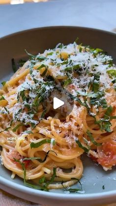 a plate full of pasta and vegetables with parmesan cheese on top, sitting on a table