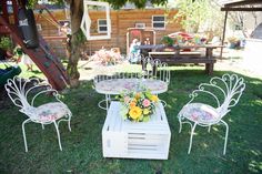 an outdoor table and chairs are set up in the grass with flowers on them,