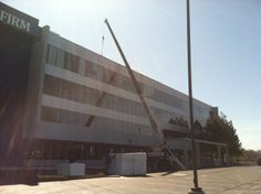 there is a crane that is on top of the truck in front of this building