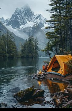 a tent is set up on the shore of a lake with mountains in the background