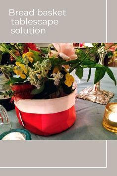 a table topped with a vase filled with flowers next to a candle and other items