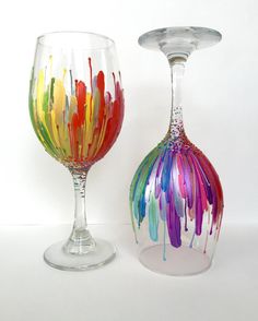 two wine glasses with different colored feathers on them, one is empty and the other has an upside down glass