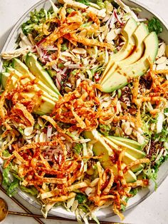 a salad with avocado, carrots and shredded cheese in it on a plate