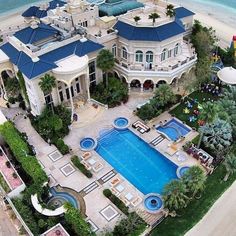 an aerial view of a mansion with a swimming pool in the foreground and beachfront