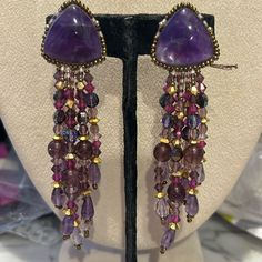 So Gorgeous!!!!! This Is A Pair Of Authentic Chipita Earrings From The 1980s. We Carried The Collection In Our Wearable Art Gallery In Ny And Just Uncovered Several Pieces That Have Been Packed Away After We Moved Locations. These May Be Over 40 Years Old But They Are Brand New. They Are Designer Stamped. This Pair Is Beautiful. It Features Genuine Amethyst Semi Precious Stones And Amethyst Cut Crystals. There Are Gold Crystal Accent Beads. These Are 4” Long And Clip On Style Earrings Signed Sto Elegant Purple Dangle Clip-on Earrings, Purple Dangle Earrings With Gemstone Accents, Purple Gemstone Accented Dangle Earrings, Purple Gemstone Dangle Earrings, Purple Bohemian Chandelier Earrings For Party, Bohemian Purple Chandelier Earrings For Party, Purple Dangle Chandelier Earrings For Party, Purple Drop Earrings With Gemstone Accents, Elegant Handmade Purple Clip-on Earrings